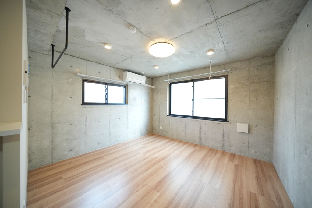 大阪府大阪市東淀川区東中島６丁目7-6celeste東中島203号室のメインルームはコンクリート打ちっぱなしの壁、杉の様なウッド調のフローリング、南面と東面に窓がついている南東角部屋、天井にはダウンライトとLEDライトがついていてモダンなデザインになっているおしゃれ部屋