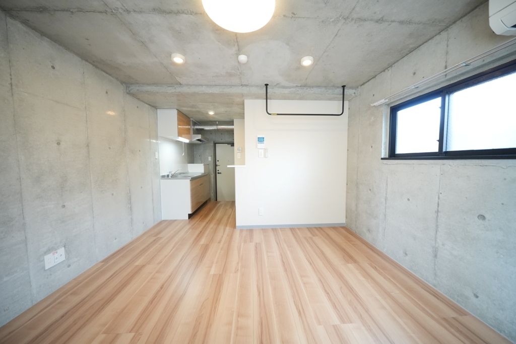 大阪府大阪市東淀川区東中島６丁目7-6celeste東中島203号室のメインルームはコンクリート打ちっぱなしの壁、杉の様なウッド調のフローリング、南面と東面に窓がついている南東角部屋、天井にはダウンライトとLEDライトがついていてモダンなデザインになっているおしゃれ部屋
